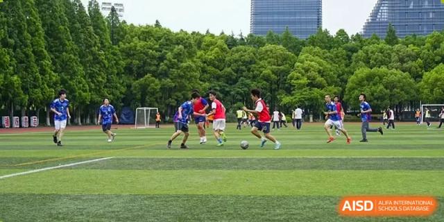 Students playing an intense game of soccer on the outdoor field at The No.2 High School Of East China Normal University (HSEFZ).