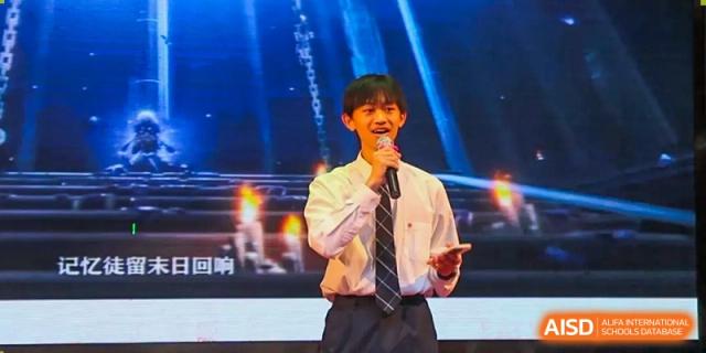 A male student in a white shirt and tie singing into a microphone during a performance or assembly at The No.2 High School Of East China Normal University (HSEFZ).