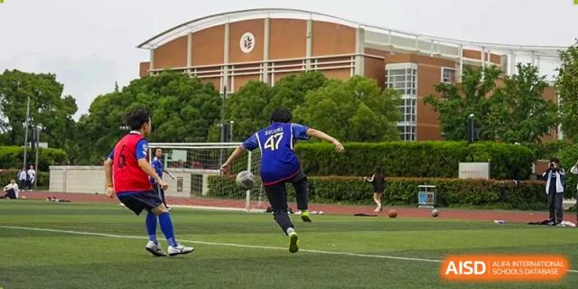 A student in a blue jersey kicking a soccer ball during an outdoor practice or game at The No.2 High School Of East China Normal University (HSEFZ).