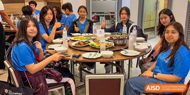 Students gathered around a table with plates of food and a laptop during a shared meal or event at The No.2 High School Of East China Normal University (HSEFZ).