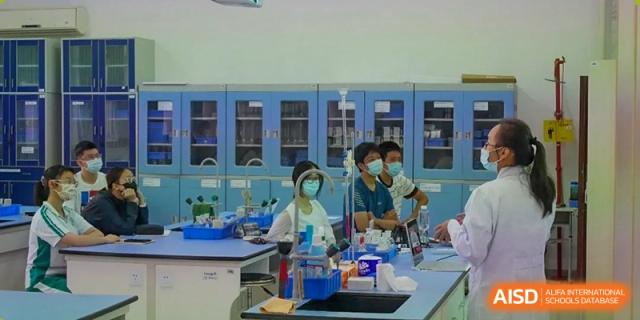 Students in lab coats are working on a science experiment with a teacher at the International Curriculum Center of RDFZ.