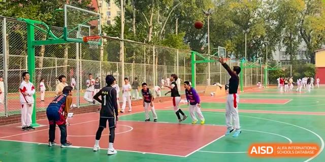 Students are playing basketball on an outdoor court, with one student attempting a shot at the International Curriculum Center of RDFZ.
