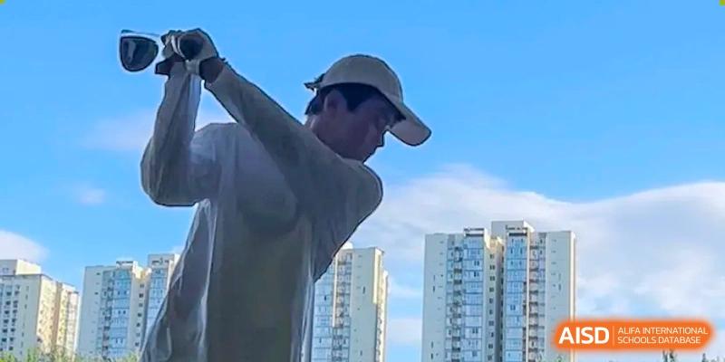 A person is wearing a white cap and hoodie, with tall buildings in the background at the International Curriculum Center of RDFZ.