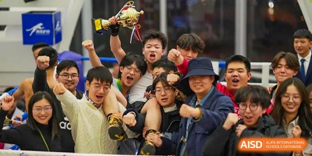 A group of students are in the stands, cheering and laughing at a sporting event at the International Curriculum Center of RDFZ.