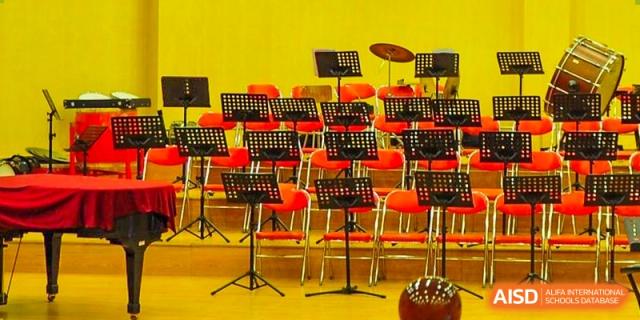 A group of chairs and music stands are set up in a room with a yellow wall at the International Curriculum Center of RDFZ.