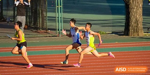 Two male athletes are sprinting side by side on a running track at the International Curriculum Center of RDFZ.