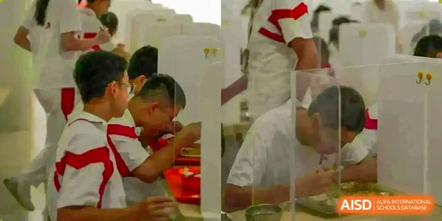 Two students in red and white uniforms are seated at a table, looking at something at the International Curriculum Center of RDFZ.
