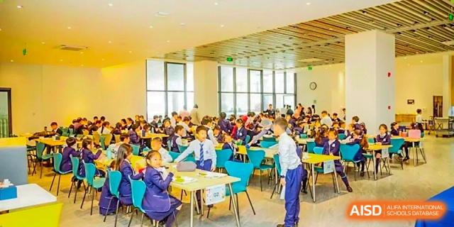 Students from ISA Science City International School are seated in a large common room during a class.