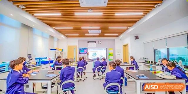 Students from ISA Science City International School are seated in rows in a classroom, with the teacher giving instructions on a smart board.