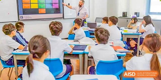 A male teacher from ISA Science City International School is helping a student with their schoolwork.