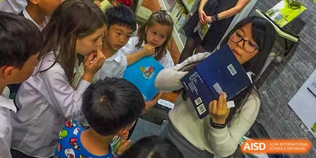 A student from ISA Science City International School is working on a science project with another student, using a digital device.