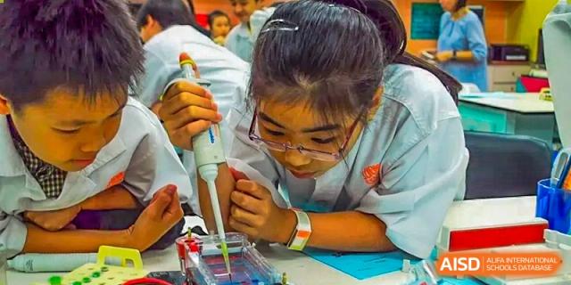 A female student from ISA Science City International School is using a pipette to transfer liquid during a science experiment.
