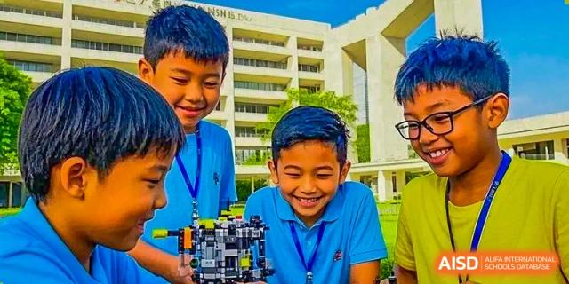 A young male student from ISA Science City International School, with blue streaks in his hair, is smiling happily.