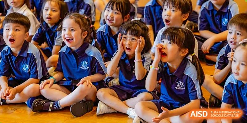 A female student from ISA Science City International School with glasses looks on with a surprised expression during an event.
