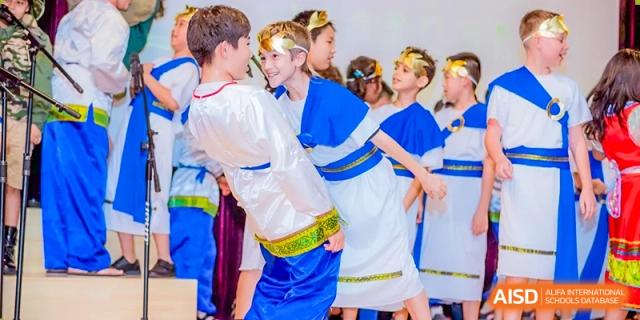 Two students from ISA Science City International School wearing blue and white outfits are playing a game with hula hoops.