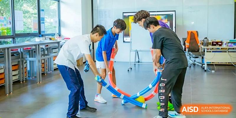A group of young students from ISA Science City International School is participating in an outdoor physical activity on a sports field.