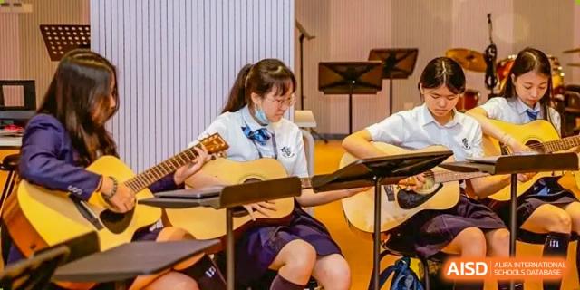 A group of students from ISA Science City International School, wearing their school uniforms, is playing flutes together on a stage.