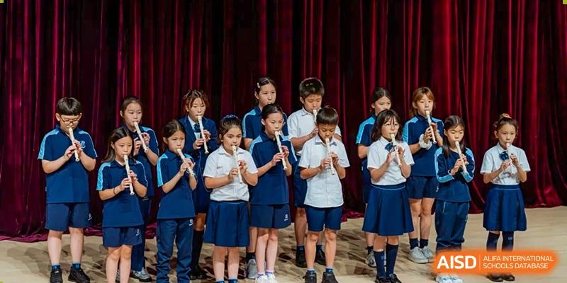 A male student from ISA Science City International School is playing the violin on a stage.