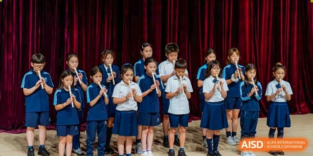 A male student from ISA Science City International School is playing the violin on a stage.