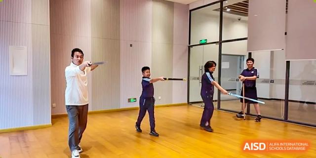 A student from ISA Science City International School, in a blue uniform, is practicing twirling a baton.