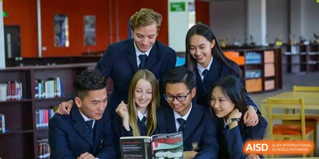 A group of high school students in uniforms studying together and looking at a book at Maple Leaf Foreign Nationals School-Yiwu.