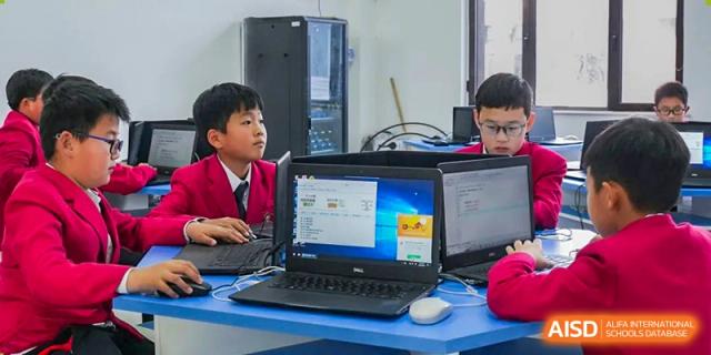 Two young students working together on a desktop computer in a classroom at Maple Leaf Foreign Nationals School-Yiwu.