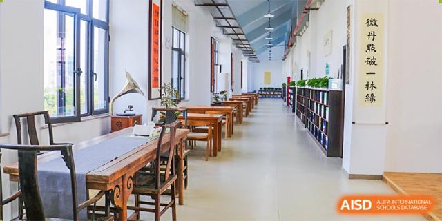 A long, brightly lit library or reading room with wooden tables and chairs at Maple Leaf Foreign Nationals School-Yiwu.
