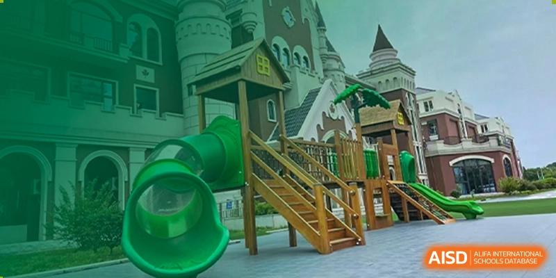 A large outdoor play structure featuring green slides, wooden stairs, and a colorful castle-like backdrop at Maple Leaf Foreign Nationals School-Yiwu.
