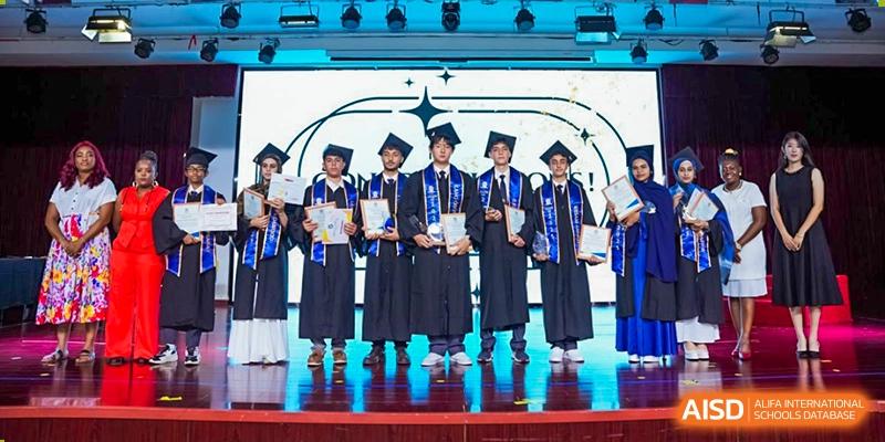 A group of graduating students in blue gowns and caps holding their diplomas on a stage at Maple Leaf Foreign Nationals School-Yiwu.