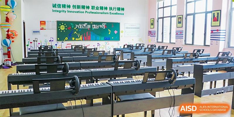 An empty music classroom featuring rows of black digital pianos/keyboards and stools at Maple Leaf Foreign Nationals School-Yiwu.