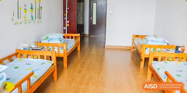 A bright, clean student dormitory room featuring wooden bed frames and light blue bedding at Maple Leaf Foreign Nationals School-Yiwu.