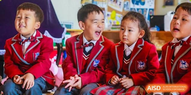 A young NANJING THOMAS SCHOOL student in uniform is laughing in a library or classroom.