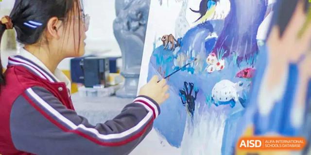 A student from NANJING THOMAS SCHOOL is painting on a canvas during an art class.