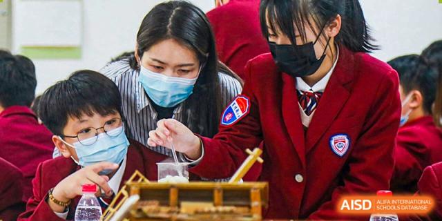 A NANJING THOMAS SCHOOL student in a mask is talking to another student.