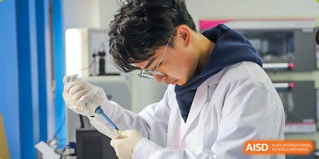 A NANJING THOMAS SCHOOL student in a lab coat is carefully performing a science experiment.