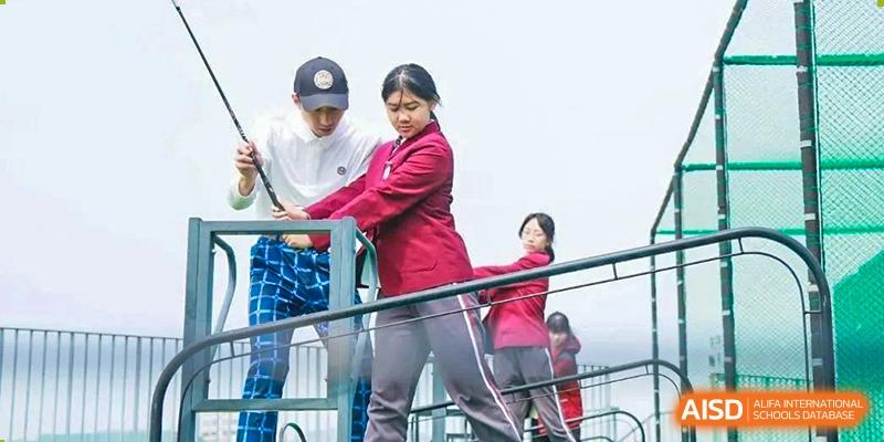 A NANJING THOMAS SCHOOL student and a teacher are on a balcony overlooking a sports area.