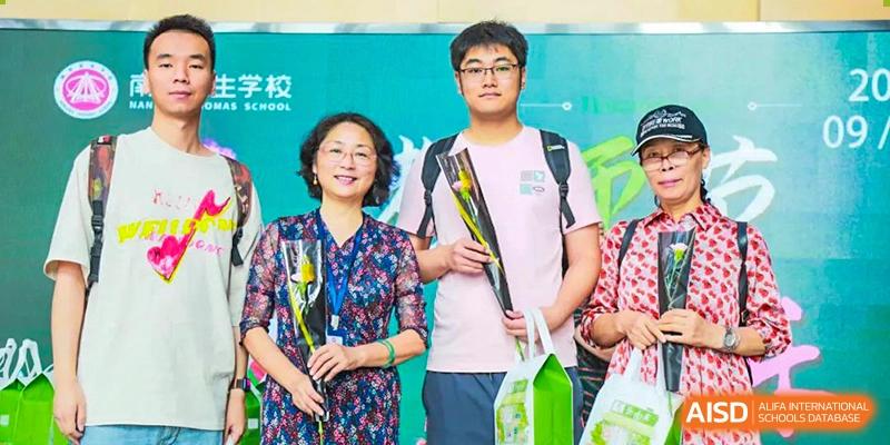 A NANJING THOMAS SCHOOL student and an adult are posing for a photo, holding flowers.