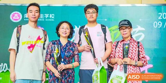 A NANJING THOMAS SCHOOL student and an adult are posing for a photo, holding flowers.