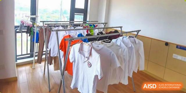 Freshly washed uniforms of NANJING THOMAS SCHOOL are hanging on a drying rack.