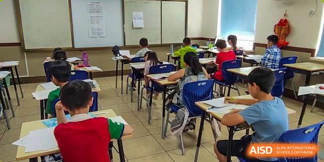 Students sitting at desks in a classroom, looking towards the front of the room, at the Qingdao Amerasia International School.