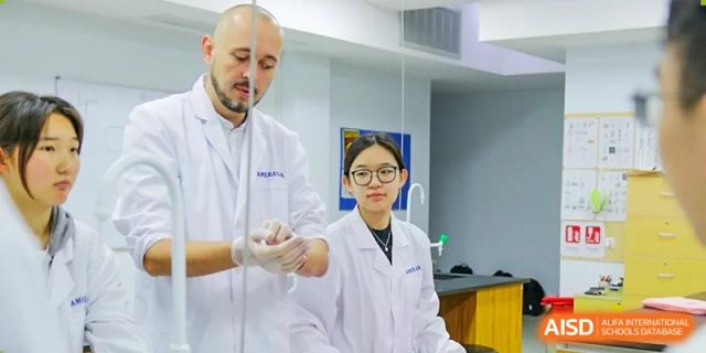 A female student in a lab coat and safety glasses holding a beaker during a science experiment at the Qingdao Amerasia International School.