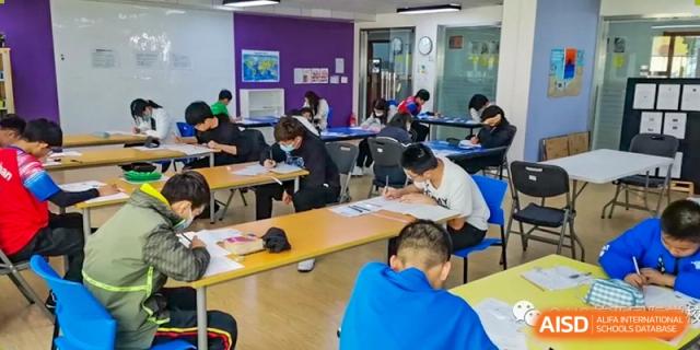 A classroom filled with students working on papers and assignments at the Qingdao Amerasia International School.