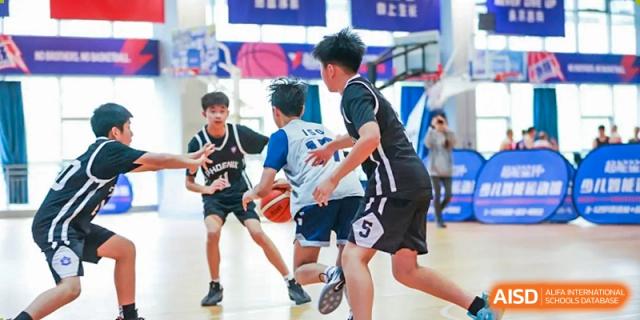 A close-up shot of two teenage boys in black and white uniforms dribbling and running with a basketball during a game at the Qingdao Amerasia International School.