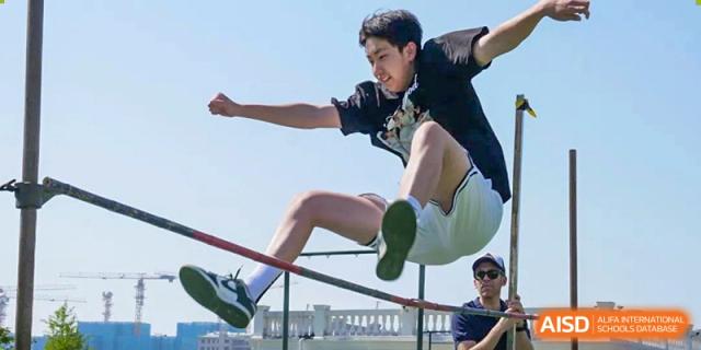 A male student clearing the bar during a high jump event at a sports competition at the Qingdao Amerasia International School.