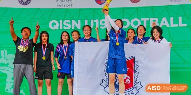 A student holding a trophy and a banner while celebrating with teammates and coaches after a soccer tournament at the Qingdao Amerasia International School.
