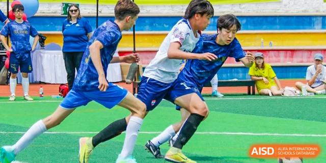 A close-up shot of students' legs as they run and compete for a soccer ball on a field at the Qingdao Amerasia International School.