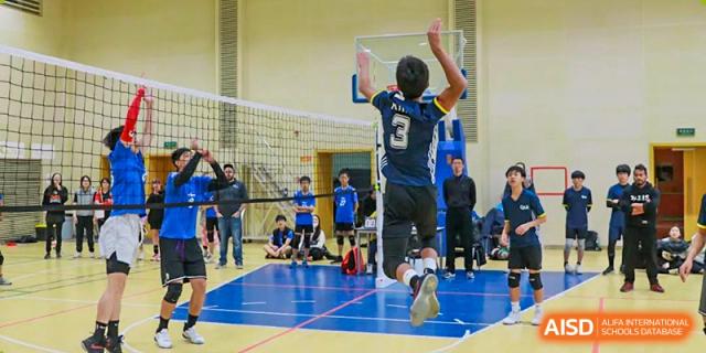 A male student jumping to spike a volleyball during a game at the Qingdao Amerasia International School.
