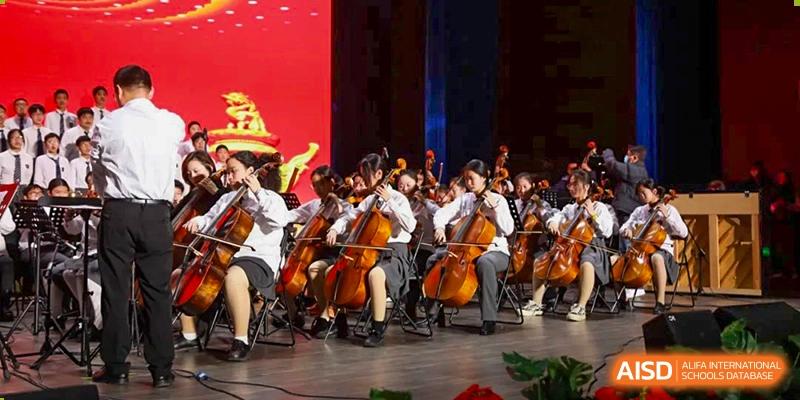 Students from Rugao International Academy BFSU playing string instruments, including cellos and violins, in an orchestra.