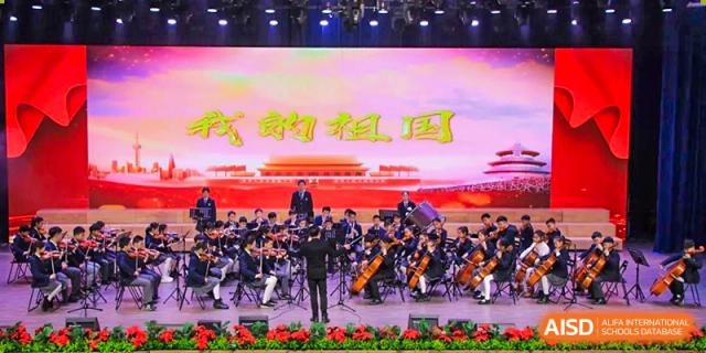 An orchestra from Rugao International Academy BFSU performing on a stage.