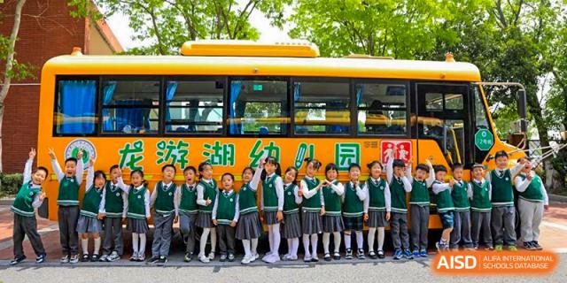 Students from Rugao International Academy BFSU standing in front of a school bus for a group photo.